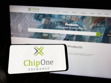 Stuttgart, Almanya - 03-26-2023: Alman dağıtım şirketi Chip 1 Exchange 'in logosuyla cep telefonu sahibi kişi iş sayfasının önünde ekranda. Telefon ekranına odaklan.