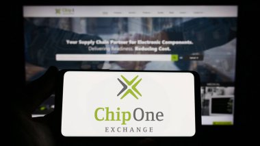 Stuttgart, Germany - 03-26-2023: Person holding smartphone with logo of German distribution company Chip 1 Exchange on screen in front of website. Focus on phone display. clipart