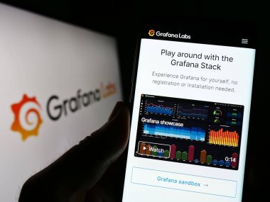 Stuttgart, Almanya - 03-26-2023: ABD 'li analitik yazılım şirketi Grafana Labs' in web sayfası logonun önünde duran kişi. Telefon ekranının merkezine odaklan.