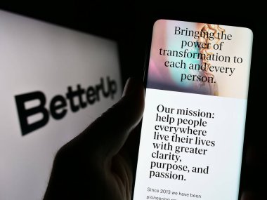 Stuttgart, Almanya - 03-26-2023: ABD 'li antrenörlük şirketi BetterUp' ın internet sayfası ile cep telefonu sahibi kişi iş logosu önünde ekranda. Telefon ekranının merkezine odaklan.