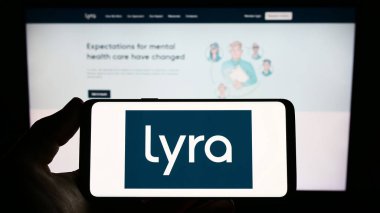 Stuttgart, Almanya - 03-26-2023: Web sitesi önünde ekranda ABD 'li akıl sağlığı şirketi Lyra Health Inc.' in logosunu taşıyan kişi. Telefon ekranına odaklan.