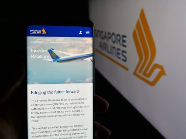 Stuttgart, Almanya - 01-20-2025: Havayolu şirketi Singapur Airlines Limited 'in web sayfası ile cep telefonu tutan kişi logonun önünde ekranda. Telefon ekranının merkezine odaklan.