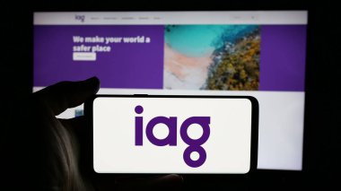 Stuttgart, Almanya - 01-22-2025: İnternet sayfası önünde Insurance Australia Group Limited (IAG) logosuna sahip cep telefonu sahibi kişi. Telefon ekranına odaklan.