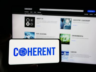 Stuttgart, Almanya - 01-22-2025: Web sitesinin önünde ekranda ABD 'li lazer donanım şirketi Conherent Inc.' in logosunun bulunduğu akıllı telefonu tutan kişi. Telefon ekranına odaklan.