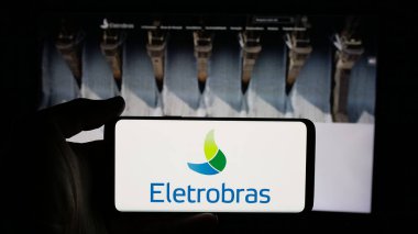 Stuttgart, Almanya - 01-23-2025: İnternet sayfasının önünde Centrais Eletricas Brasileiras S.A. (Electrobras) logosu olan cep telefonu sahibi kişi. Telefon ekranına odaklan.