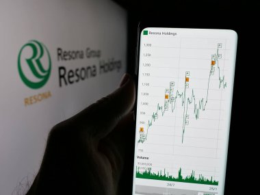 Stuttgart, Almanya - 01-23-2025: Japon bankacılık şirketi Resona Holding Inc. 'nin web sayfası ile logo önünde cep telefonu tutan kişi. Telefon ekranının merkezine odaklan.