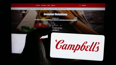 Stuttgart, Almanya - 01-23-2025: ABD gıda işleme şirketi logosu olan cep telefonu sahibi kişi The Campbell 's Company web sayfasının önünde ekranda. Telefon ekranına odaklan.