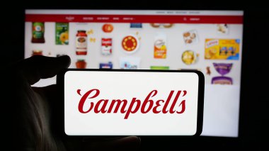 Stuttgart, Almanya - 01-23-2025: ABD gıda işleme şirketi logosu olan cep telefonu sahibi kişi The Campbell Company web sayfasının önünde ekranda. Telefon ekranına odaklan.
