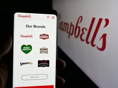 Stuttgart, Almanya - 01-23-2025: ABD gıda işleme şirketi The Campbell Company 'nin internet sayfası ile cep telefonu tutan kişi logolu ekranda. Telefon ekranının merkezine odaklan.