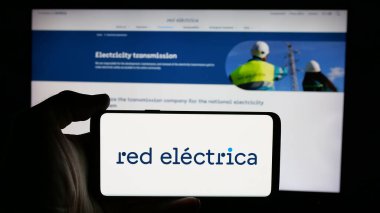 Stuttgart, Almanya - 01-23-2025: İspanyol Red Electrica de Espana (REE) şirketinin logosunun bulunduğu cep telefonu sahibi kişi iş sayfası önünde ekranda. Telefon ekranına odaklan.