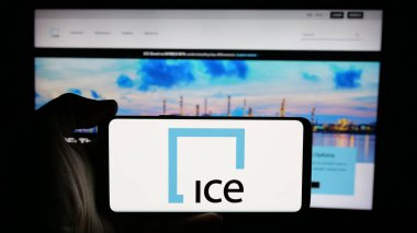 Stuttgart, Almanya - 01-23-2025: İnternet sayfası önünde üzerinde Kıtalararası Borsa A.Ş. logosu olan cep telefonu sahibi kişi. Telefon ekranına odaklan.