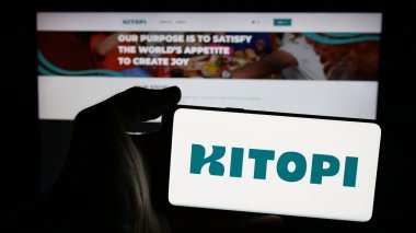 Stuttgart, Almanya - 01-23-2025: Arap gastronomi şirketi Kitopi 'nin logosunun bulunduğu cep telefonu sahibi kişi iş sayfasının önünde ekranda. Telefon ekranına odaklan.