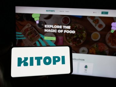 Stuttgart, Almanya - 01-23-2025: Arap gastronomi şirketi Kitopi 'nin logosuna sahip akıllı telefon sahibi kişi web sitesinin önünde ekranda. Telefon ekranına odaklan.