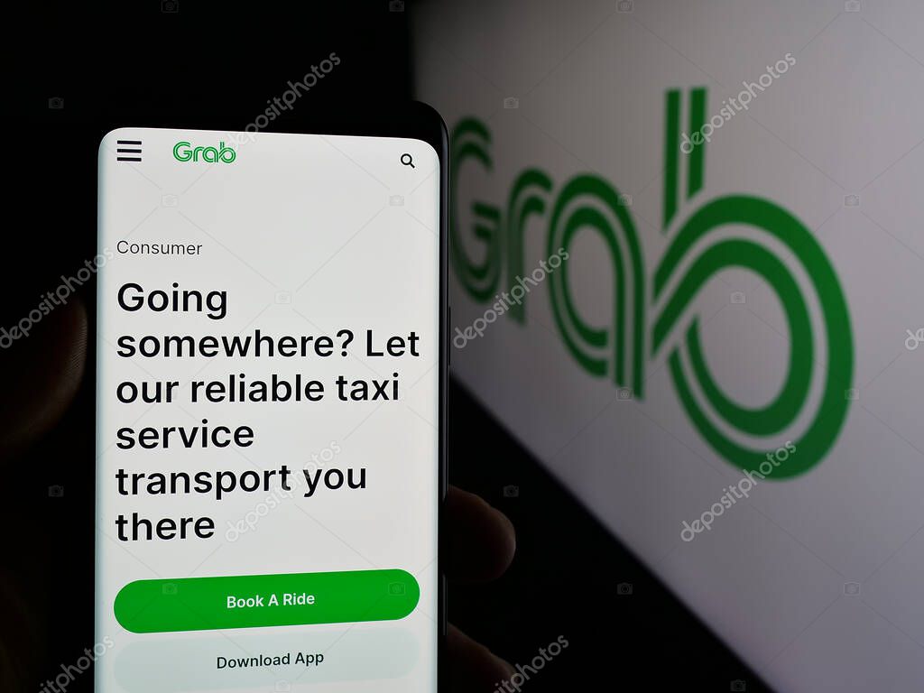 Stuttgart, Germany - 01-23-2025: Person holding mobile phone with web page of Singaporean technology company Grab Holdings Inc. on screen with logo. Focus on center of phone display.