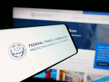 Stuttgart, Germany - 01-24-2025: Smartphone with logo of American government agency Federal Trade Commission (FTC) on screen in front of website. Focus on left of phone display. clipart