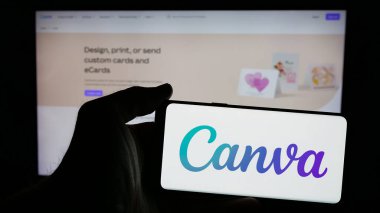 Stuttgart, Almanya - 01-24-2025: Avustralyalı grafik tasarım şirketi Canva Pty 'nin logosuna sahip cep telefonu sahibi kişi. Ltd. Web sayfasının önünde ekranda. Telefon ekranına odaklan.