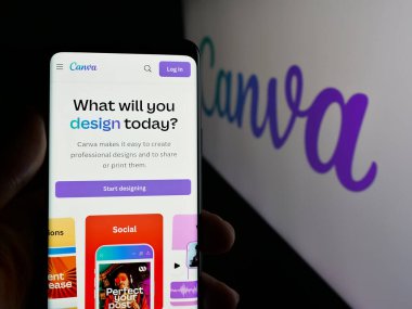 Stuttgart, Almanya - 01-24-2025: Avustralyalı grafik tasarım şirketi Canva Pty 'nin web sayfası ile cep telefonu tutan kişi. Ltd. Ekranda logo var. Telefon ekranının merkezine odaklan.
