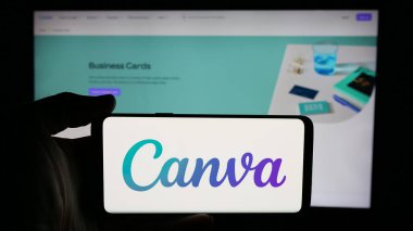 Stuttgart, Almanya - 01-24-2025: Avustralyalı grafik tasarım şirketi Canva Pty 'nin logosuyla cep telefonu tutan kişi. Ltd. Web sayfasının önünde ekranda. Telefon ekranına odaklan.
