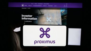 Stuttgart, Germany - 01-28-2025: Person holding cellphone with logo of Belgian telecommunications company Proximus Group on screen in front of webpage. Focus on phone display. clipart