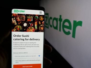 Stuttgart, Almanya - 01-28-2025: ABD 'li pazar yeri şirketi ezCater Inc.' in internet sayfası ile cep telefonu sahibi kişi logolu ekranda. Telefon ekranının merkezine odaklan.