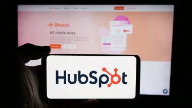 Stuttgart, Almanya - 01-28-2025: ABD 'li pazarlama yazılım şirketi HubSpot Inc.' in logosuyla cep telefonu sahibi kişi iş sayfasının önünde ekranda. Telefon ekranına odaklan.