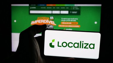 Stuttgart, Almanya - 01-28-2025: Brezilyalı firma Localiza Rent a Car SA 'nın logosunun bulunduğu cep telefonu sahibi kişi iş sayfasının önünde ekranda. Telefon ekranına odaklan.