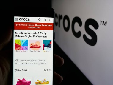 Stuttgart, Almanya - 01-28-2025: ABD 'li ayakkabı şirketi Crocs Inc.' in web sayfası olan akıllı telefon sahibi kişi logonun önünde ekranda. Telefon ekranının merkezine odaklan.
