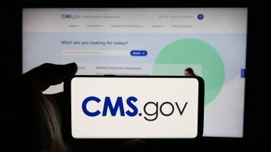 Stuttgart, Almanya - 01-28-2025: İnternet sayfası önünde üzerinde Medicare Medicaid Services (CMS) logosu bulunan kişi. Telefon ekranına odaklan.