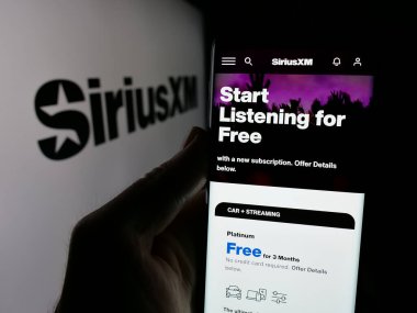 Stuttgart, Almanya - 01-28-2025: ABD 'li yayın şirketi Sirius XM Holding Inc.' in web sayfası ile cep telefonu elinde bulunan kişi logo ile ekranda. Telefon ekranının merkezine odaklan.