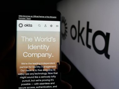 Stuttgart, Almanya - 01-29-2025: ABD kimlik yönetim şirketi Okta Inc. 'nin web sayfası ile akıllı telefon sahibi kişi logo önünde ekranda. Telefon ekranının merkezine odaklan.