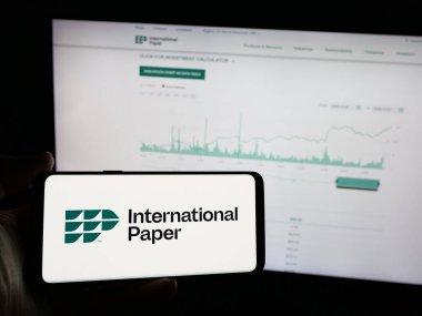 Stuttgart, Almanya - 01-29-2025: İnternet sitesi önünde üzerinde ABD 'li Uluslararası Kağıt Şirketi logosu bulunan kişi. Telefon ekranına odaklan.