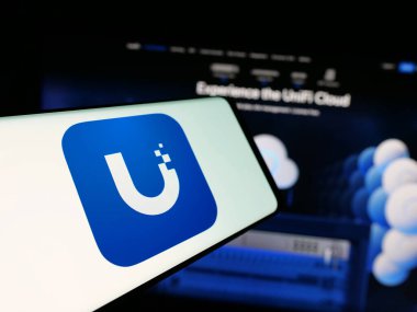 Stuttgart, Almanya - 01-30-2025: Amerikan teknoloji şirketi Ubiquiti Inc. 'in logosuna sahip akıllı telefon, iş dünyasının web sitesinin önünde ekranda. Telefon ekranının merkez soluna odaklan.