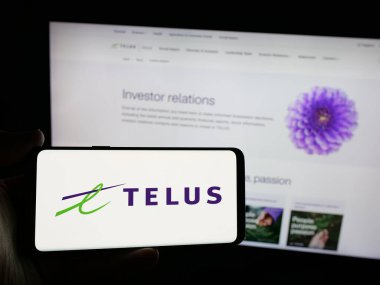 Stuttgart, Almanya - 01-30-2025: Kanadalı telekomünikasyon şirketi Telus Corporation 'ın logosunu elinde tutan kişi web sitesinin önünde ekranda. Telefon ekranına odaklan.