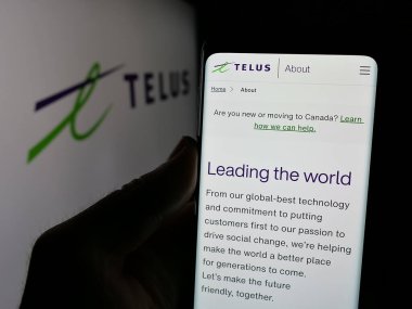 Stuttgart, Almanya - 01-30-2025: Kanadalı telekomünikasyon şirketi Telus Corporation 'ın internet sayfası ile cep telefonu tutan kişi logolu ekranda. Telefon ekranının merkezine odaklan.
