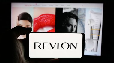Stuttgart, Almanya - 01-30-2025: ABD 'li kozmetik şirketi Revlon Inc.' in logosunun bulunduğu cep telefonu sahibi kişi iş sayfasının önünde ekranda. Telefon ekranına odaklan.