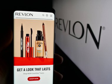 Stuttgart, Almanya - 01-30-2025: ABD 'li kozmetik şirketi Revlon Inc.' in web sayfası ile akıllı telefon sahibi kişi logonun önünde ekranda. Telefon ekranının merkezine odaklan.