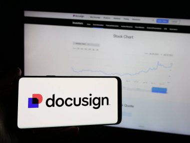 Stuttgart, Almanya - 01-30-2025: İnternet sitesinin önünde üzerinde ABD 'li yazılım şirketi Docusign Inc.' in logosu olan akıllı telefonu tutan kişi. Telefon ekranına odaklan.