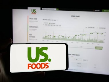 Stuttgart, Almanya - 01-31-2025: İnternet sitesinin önünde ekranda US Foods Holding Corp. 'un logosunun bulunduğu akıllı telefonu tutan kişi. Telefon ekranına odaklan.