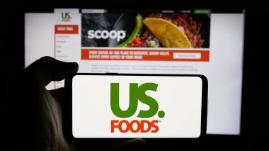Stuttgart, Almanya - 01-31-2025: US Foods Holding Corp. adlı gıda şirketinin logosuyla cep telefonu sahibi kişi iş sayfasının önünde ekranda. Telefon ekranına odaklan.