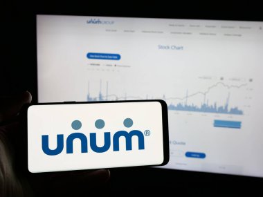 Stuttgart, Almanya - 01-31-2025: Web sitesi önünde ekranda ABD 'li sigorta şirketi Unum Group' un logosunun bulunduğu akıllı telefonu tutan kişi. Telefon ekranına odaklan.