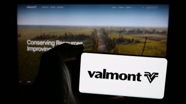 Stuttgart, Almanya - 01-31-2025: Amerikan şirketi Valmont Industries Inc. 'in logosunun bulunduğu cep telefonu sahibi kişi iş sayfasının önünde ekranda. Telefon ekranına odaklan.