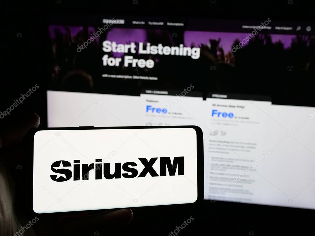 Stuttgart, Germany - 01-28-2025: Person holding smartphone with logo of US broadcasting company Sirius XM Holdings Inc. on screen in front of website. Focus on phone display.