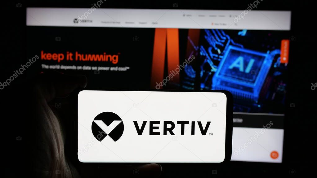 Stuttgart, Germany - 01-31-2025: Person holding cellphone with logo of US technology company Vertiv Holdings Co. on screen in front of business webpage. Focus on phone display.