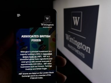 Stuttgart, Almanya - 01-31-2025: Wittington Yatırımcılık Limited şirketinin web sitesi bulunan cep telefonu logolu kişi. Telefon ekranının merkezine odaklan.