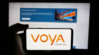 Stuttgart, Almanya - 01-31-2025: ABD 'li finans şirketi Voya Financial Inc.' in logosuyla cep telefonu sahibi kişi iş sayfasının önünde ekranda. Telefon ekranına odaklan.