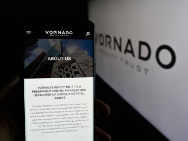 Stuttgart, Almanya - 01-31-2025: ABD 'li emlak şirketi Vornado Emlak Trust' ın web sayfası ve logosu olan cep telefonu sahibi kişi. Telefon ekranının merkezine odaklan.