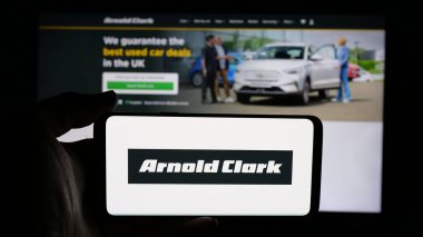 Stuttgart, Almanya - 03-04-2025: Araba satıcısı Arnold Clark Automobiles Ltd. 'nin logosunun bulunduğu cep telefonu sahibi kişi iş sayfasının önünde ekranda. Telefon ekranına odaklan.