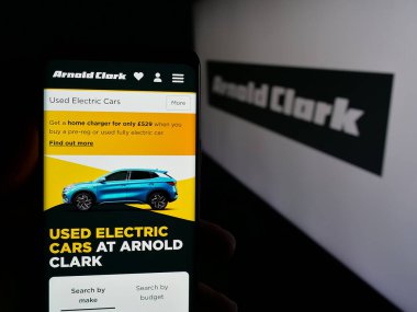 Stuttgart, Almanya - 03-04-2025: Araba satıcısı Arnold Clark Automobiles Ltd. 'nin web sitesi ile cep telefonu tutan kişi logonun önünde ekranda. Telefon ekranının merkezine odaklan.
