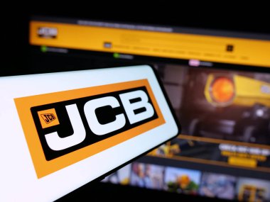 Stuttgart, Almanya - 03-04-2025: İngiliz J.C. Bamford Excavators Limited (JCB) şirketinin logosuna sahip akıllı telefon iş sitesinin önünde ekranda. Telefon ekranının merkez soluna odaklan.