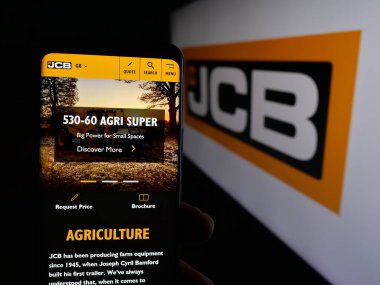 Stuttgart, Almanya - 03-04-2025: İngiliz J.C. Bamford Excavators Limited (JCB) şirketinin web sayfası logonun önünde duran kişi. Telefon ekranının merkezine odaklan.
